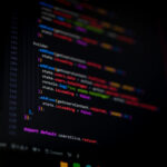 Tekst programistyczny na ciemnym tle z kolorowymi liniami kodu.